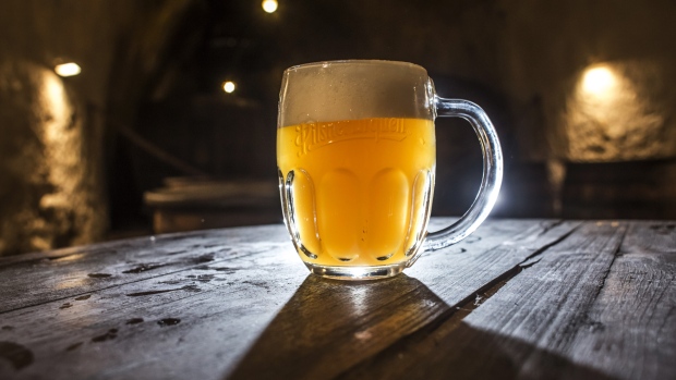 A glass of beer sits on a table near wooden vats at the Pilsner Urquell brewery, operated by SABMiller Plc, in Plzen, Czech Republic, on Monday, Dec. 7, 2015. Carrying the Czech Beer label requires the use of specific types of Czech-grown barley and hops that give the domestic brew its characteristic bitterness, aroma and drinkability, said Vladimir Balach, the head of the Czech Beer and Malt Association in a 2014 interview.