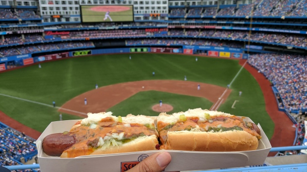 A spectator holds up a hot dog at a Blue Jays game in Toronto