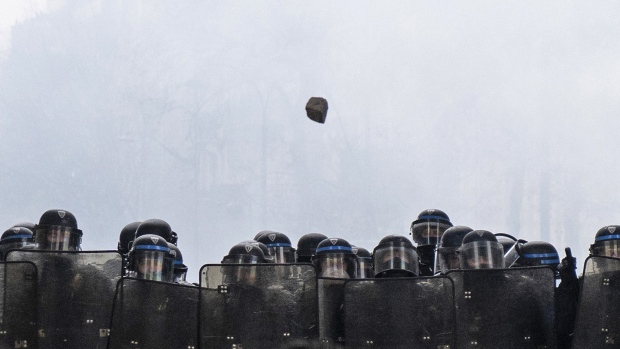 A paving stone hurtles toward riot police in Paris. Photographer: Veronique de Viguerie/Getty Images Europe
