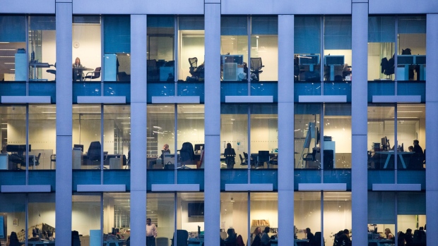 Office workers sit inside an illuminated office building in London, U.K., on Thursday, Nov. 22, 2018. Brexit Britain will be the top destination for major European investors to snap up commercial property next year, according to a survey of executives managing more than 500 billion pounds ($640 billion) of real estate conducted by Knight Frank. 