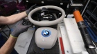 An employee reaches for a steering wheel before fitting to a BMW i3 electric automobile