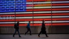 Pedestrians walk past an illuminated American flag in the Times Square area of New York, U.S., on Friday, April 26, 2019. U.S. stocks edged higher on better-than-forecast earnings while Treasury yields fell after data signaled tepid inflation in the first quarter. Photographer: Michael Nagle/Bloomberg