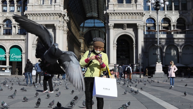 MILAN, ITALY - FEBRUARY 28: A pigeon flies over a woman wearing a protective mask in the Duomo Square on February 28, 2020 in Milan, Italy.
