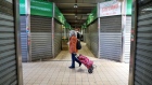 A customer wearing a protective face mask walks past closed stalls at an indoor market in Rome, Italy, on Friday, March 27, 2020. European Union leaders failed to agree on key details of economic rescue measures, as Italy's coronavirus infections surged despite weeks of restrictions on public life, worsening Europes human cost. Photographer: Alessia Pierdomenico/Bloomberg