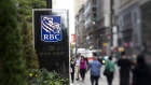 Pedestrians pass in front of RBC Royal Bank signage outside the company's office in this photo taken with a tilt-shift lens near Bay Street in Toronto. Photographer: Brent Lewin/Bloomberg
