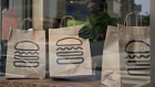 An employee wearing a protective mask picks up a take-out order at Shake Shack. Photographer: Andrew Harrer/Bloomberg
