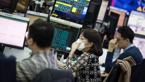 A foreign currency dealer wearing a protective mask works in a dealing room of Hana Bank in Seoul, South Korea, on Friday, Feb. 28, 2020. Fear tightened its grip on global markets Friday, with European stock futures tumbling 4% and U.S. contracts signaling yet more pain after the biggest one-day rout on Wall Street since 2011. Photographer: SeongJoon Cho/Bloomberg