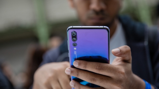 An attendee inspects a P20 Pro smartphone, manufactured by Huawei Technologies Co., during its unveiling in Paris, France, on Tuesday, March 21, 2018. Huawei Technologies Co. is launching the P20 as an upgrade to the higher end of its flagship smartphones, walking in the footsteps of rival Samsung Electronics Co. by betting heavily on the camera. Photographer: Marlene Awaad/Bloomberg