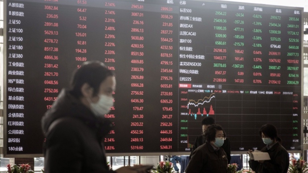 Employees and visitors wearing protective masks walk past an electronic stock board at the Shanghai Stock Exchange in Shanghai, China, on Monday, March 2, 2020. The pressure to get China back to work after the coronavirus shutdown is resurrecting an old temptation: doctoring data so it shows senior officials what they want to see. Photographer: Qilai Shen/Bloomberg
