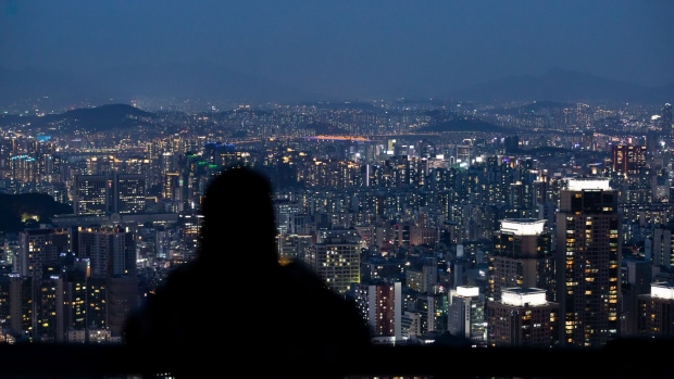 A woman is silhouetted as she looks at a city skyline from an observation deck of Woomyeon mountain at dusk in Seoul, South Korea, on Thursday, July 9, 2020. South Korea’s government is preparing new regulations to curb excessive house price gains that have fueled public discontent over inequality and property speculation. Photographer: SeongJoon Cho/Bloomberg