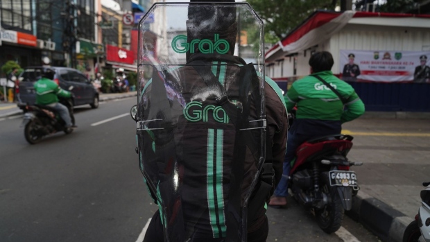 A Grab Holdings Inc. courier wears a protective shield on their back while making deliveries in Jakarta, Indonesia, on Wednesday, July 8, 2020. Authorities will step up surveillance and enforcement of social distancing rules in 300 traditional markets and public transport services to stem the spread of the virus.