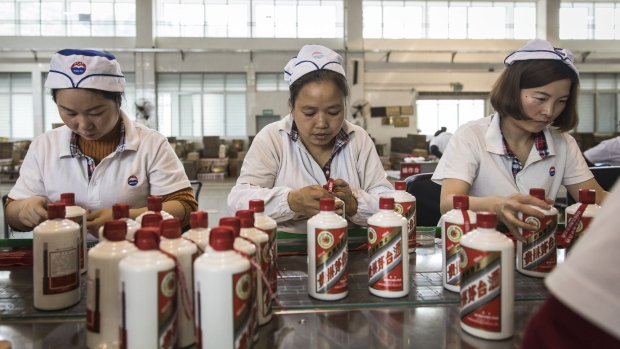 Employees tie ribbons onto bottles of Moutai baijiu on the production line at the Kweichow Moutai Co. factory in the town of Maotai in Renhuai, Guizhou province, China.