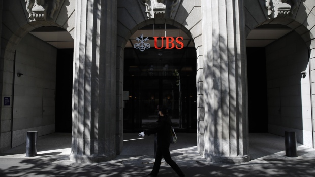 A pedestrian wearing protective gloves walks past the entrance to the UBS Group AG headquarters in Zurich, Switzerland, on Friday, April 17, 2020. A UBS appeal of a record 4.5 billion-euro ($4.9 billion) French fine for helping clients stash undeclared funds in offshore accounts was postponed over concerns related to coronavirus pandemic, according to people familiar with the case.