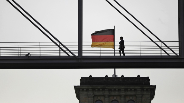 Pedestrians use a walkway connecting government buildings near a German national flag flying from the Reichstag in Berlin, Germany, on Thursday, Oct. 8, 2020. German lawmakers sought to lay some of the blame on Finance Minister Olaf Scholz for the failure to detect wrongdoing at Wirecard, as a parliamentary inquiry into the collapse of the digital-payments company gets underway in Berlin. Photographer: Krisztian Bocsi/Bloomberg