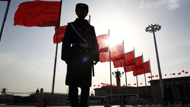 A paramilitary police officer stands guard in front of red flags at Tiananmen Square in Beijing, China, on Monday, March 2, 2015. China's annual meeting of the National People's Congress, which begins March 5 in Beijing, is expected to set government policies for the year on issues ranging from economic growth to military spending and pollution. Photographer: Bloomberg/Bloomberg