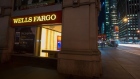 Pedestrians pass in front of a Wells Fargo & Co. bank branch at night in New York.