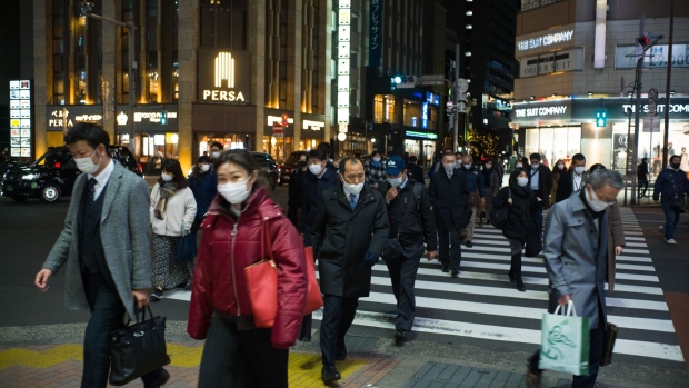 Evening commuters wearing protective masks cross a street in Tokyo, Japan, on Friday, Jan. 8, 2021. The state of emergency over the coronavirus that went into effect Friday for Tokyo and its surrounding area will weigh on Japans economy this quarter, said Japan's Finance Minister Taro Aso. Photographer: Kentaro Takahashi/Bloomberg