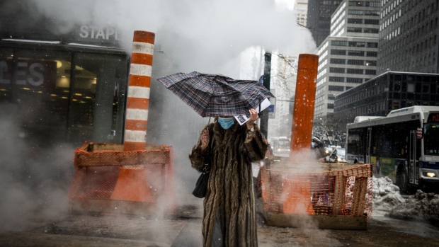 A pedestrian wearing protective masks holds an umbrella while crossing a street after a winter storm in New York on Feb. 2. Photographer: Mark Kauzlarich/Bloomberg