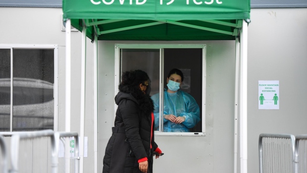 A visitor talks to an worker at a Covid-19 testing service near the Radisson Blu Edwardian hotel, a location used for travelers quarantine, at London Heathrow Airport in London, U.K., on Monday, Feb. 15, 2021. Some passengers traveling to the U.K. will face tougher quarantine measures, including enforced stays in hotels, repeated tests, and the threat of fines and even jail. Photographer: Chris J. Ratcliffe/Bloomberg