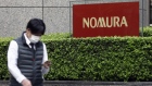 A pedestrian wearing a protective face mask walks past the Nomura Holdings Inc. signage outside its headquarters in Tokyo, Japan, on Monday, March 29, 2021. Nomura's warning of a "significant" potential loss from an unnamed U.S. client is related to the unwinding of trades by Bill Hwangs Archegos Capital Management, according to people familiar with the matter. Photographer: Kiyoshi Ota/Bloomberg