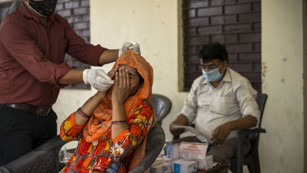 A health worker takes a swab sample at a Covid-19 testing site set up at the Panchayat house of a village in the Gautam Budh Nagar district of Noida, Uttar Pradesh, India, on Sunday, May 30, 2021. The resilience of the Indian economy -- which is on track to grow 10% in the year that began April 1, according to the median of 12 estimates compiled by Bloomberg News -- will be tested by its ability to overcome a devastating outbreak of Covid-19. Photographer: Anindito Mukherjee/Bloomberg
