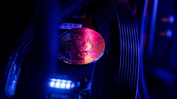                             A token representing Bitcoin virtual currency sits among cables and LED lighting inside a 'mining rig' computer in this ar