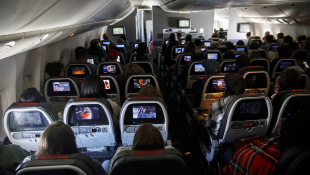 Passengers watch inflight entertainment (IFE) while sitting in economy class during an American Airlines Group Inc. Boeing 777-200 flight from Los Angeles International Airport (LAX) in Los Angeles, California, U.S., on Thursday, Oct. 1, 2020. American Airlines Group Inc. and United Airlines Holdings Inc.will start laying off thousands of employees as scheduled, spurning Treasury Secretary Steven Mnuchin’s appeal for a delay as he negotiates with Congress over an economic relief plan that includes payroll support for U.S. carriers. Photographer: Patrick T. Fallon/Bloomberg