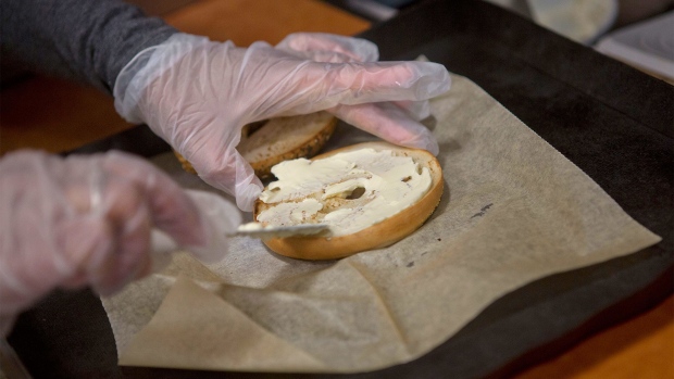 A worker spreads cream cheese onto a bagel at a bagel store in New York. Photographer: Spencer Platt/Getty Images