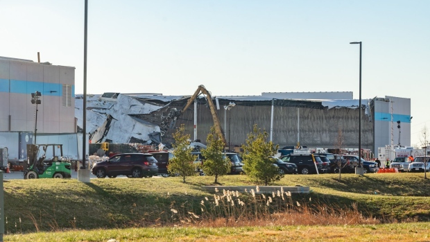 An excavator removes debris from a collapsed roof at an Amazon warehouse following a tornado in Edwardsville, Illinois, U.S., on Sunday, Dec. 12, 2021. Tornadoes ripped across several U.S. states late Friday, killing at least six at a Amazon warehouse that was partially flattened in Illinois.