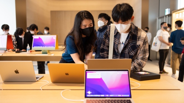 An employee, left, assists a customer using an Apple Inc. Macbook Pro laptop computer at the company's Myeongdong store during its opening in Seoul, South Korea, on Saturday, April 9, 2022. The two-level store in the center of the city is Apple's third store in South Korea.