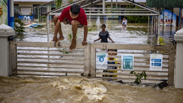 SAN ILDEFONSO, PHILIPPINES - SEPTEMBER 26: Children climb a gate of a school flooded by Super Typhoon Noru on September 26, 2022 in San Ildefonso, Bulacan province, Philippines. Super Typhoon Noru made landfall in the Philippines overnight, causing widespread flooding and leaving at least five dead. High winds and heavy rains have flattened villages and have increased the threat of landslides. (Photo by Ezra Acayan/Getty Images)