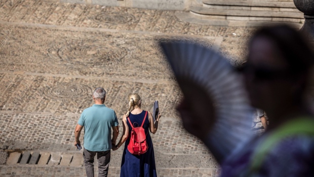 Tourists use hand fans during high temperatures in the old town area of Girona, Spain, in August 2023. Photographer: Angel Garcia/Bloomberg