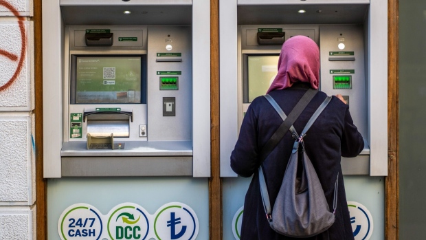 A customer uses an automated teller machine outside a bank in Izmir, Turkey. Photographer: Moe Zoyari/Bloomberg
