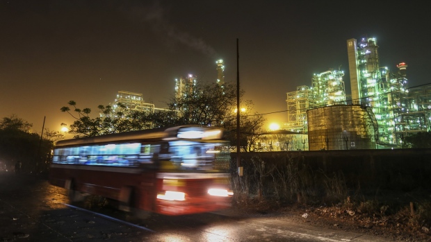 A bus passes a Bharat Petroleum Corp. refinery illuminated at night in the Mahul area of Mumbai