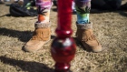 A resident wears socks featuring marijuana leaf while standing behind a bong during the 420 Day festival on the lawns of Parliament Hill in Ottawa, Ontario, Canada, on Friday, April 20, 2018. Canada's marijuana industry is projected to reach as much as C$12 billion a year in sales, as the nation prepares for recreational legalization later this year.