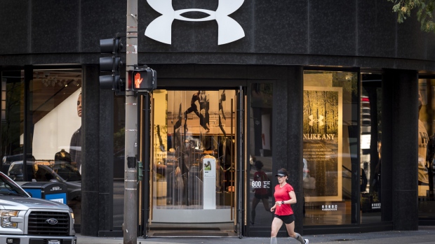 A woman runs past an Under Armour Inc. store in downtown Chicago, Illinois, U.S., on Monday, Oct. 16, 2017. Under Armour must improve and expand its footwear business to counter constant challenges to its apparel market share from new entrants, most recently Amazon.com.