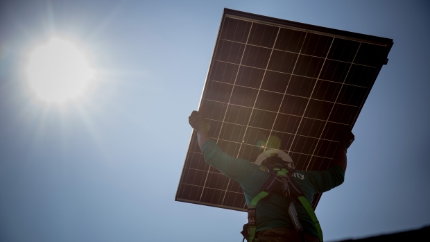 A SolarCity Corp. employee carries a solar panel on the roof during installation at a home in Kendall Park, New Jersey, U.S., on Tuesday, July 28, 2015.
