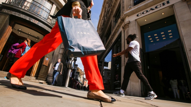 A shopper caries a Zara clothing retailer bag as shes passes a Gap Inc. retail store, left, and a Coach retail store in Regent Street in London, U.K., on Tuesday, April 17, 2018. 