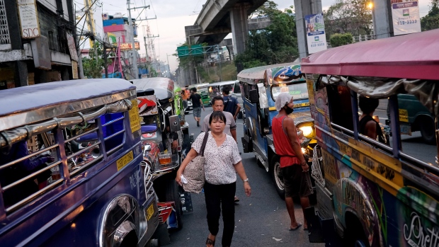 A pedestrian walks between jeepneys waiting for commuters in Manila, the Philippines, on Sunday, April 9, 2017. Smoke-belching jeepneys are as iconic to Manila as the cable cars of San Francisco, the gondolas on Venice's canals and the black cabs in London. The most popular public transport in the Philippines is now being targeted for the scrap heap as President Rodrigo Duterte tries to modernize the nation and clean up its air. 