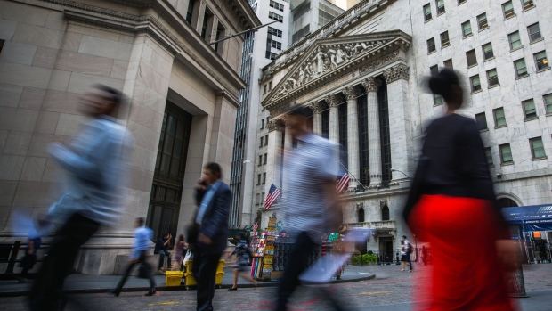 Pedestrians walk along Wall Street near the New York Stock Exchange (NYSE) in New York, U.S., on Monday, Aug. 14, 2017. 