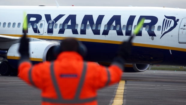 An employee uses glow sticks to guide a Ryanair Holdings Plc aircraft into position at Dublin Airport, operated by Dublin Airport Authority, in Dublin, Ireland, on Friday, Nov. 25, 2016. Ryanair provides low fare passenger airline services to destinations in Europe. 