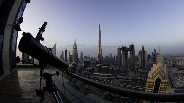 A telescope sits on the outdoor deck of a skyscraper overlooking the city skyline towards the Burj Khalifa tower, center, and the Address Sky View, center right, under construction by developers Emaar Properties PJSC, in Dubai, United Arab Emirates, on Wednesday, April 11, 2018. Transformed into a flamboyant city state from an impoverished Gulf port in less than 50 years, Dubai defied geology to build skyscrapers and elaborately shaped islands in the sea. 