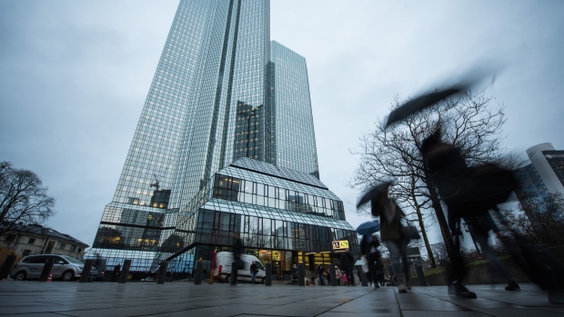 Pedestrians shelter under umbrellas as the twin tower skyscraper headquarters of Deutsche Bank AG stand in Frankfurt, Germany, on Friday, Feb. 2, 2018. Germany’s largest lender just closed out another year in the red, with revenue that declined to the lowest in seven years in the fourth quarter. 