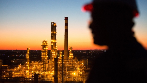 A worker stands on a high level platform and looks out across an illuminated oil refinery in Kazakhstan. 