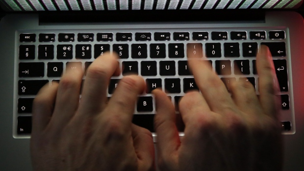 A stream of binary coding, text or computer processor instructions, is seen displayed on a laptop computer screen as a man works to enter data on the computer keyboard in this arranged photograph in London, U.K., on Wednesday, Dec. 23, 2015. 