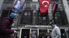 Pedestrians pass a carpet store decorated with a Turkish national flag and image of Kemal Ataturk, founder of modern Turkey, in Istanbul, Turkey, on Tuesday, Jan. 3, 2017. Turkey’s lira weakened the most among major world currencies on Tuesday, falling as much as 1.7 percent to a new record, as the killer of 39 people at an Istanbul nightclub remained at large and inflation accelerated more than estimates in December. 