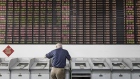 An investor stands at a trading terminal in front of an electronic stock board at a securities brokerage in Shanghai, China, on Friday, June 9, 2017. The Shanghai Composite Index rose 0.1 percent to extend a weekly gain to 1.5 percent. 
