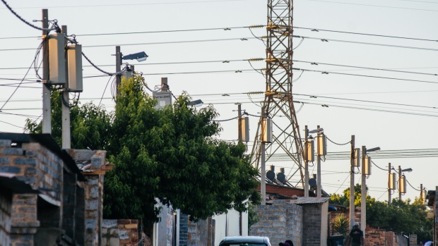 A pylon tower carries electrical power lines over residential shacks and electrical boxes in the Alexandra township outside Johannesburg, South Africa, on Thursday, Oct. 6, 2016. Eskom Holdings SOC Ltd. is building new electricity stations to end the power cuts that were imposed for about 100 days last year, curbing growth in Africa's most-industrialized nation. 