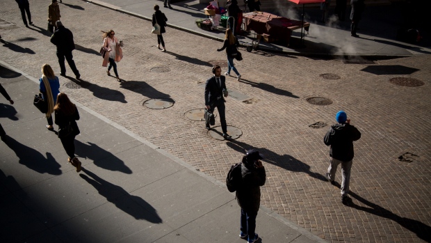 Pedestrians cast shadows as they walk on Wall Street near the New York Stock Exchange (NYSE) in New York, U.S. 