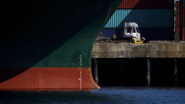 A truck drives past a container ship at the Port of Los Angeles in Los Angeles, California, U.S., on Wednesday, March 28, 2018. Long-only exchange-traded funds (ETFs) linked to broad baskets of energy, metals and agricultural products attracted $2.66 billion this quarter, Bloomberg Intelligence estimates show. While that's the largest quarterly inflow in data going back to 2005, the stream of money slowed in March as the U.S.-China trade row clouded the outlook for economic growth. 